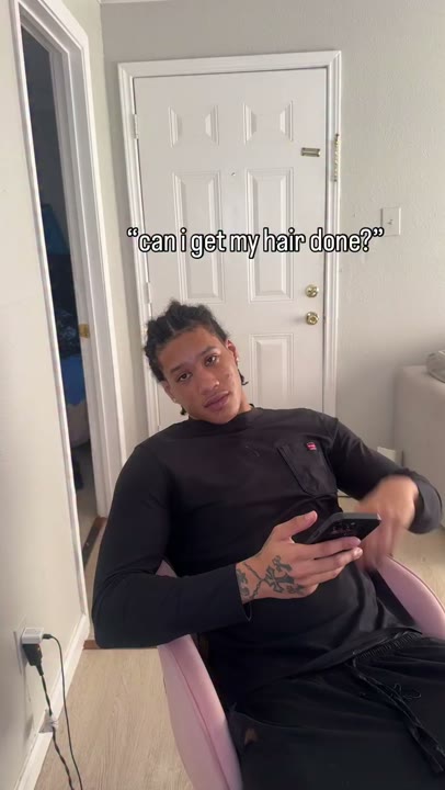 Frame at 0 seconds: The seated creator requests hair styling through the overlay “can i get my hair done?”