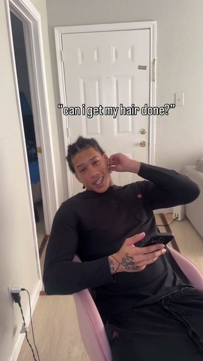 Frame at 1 seconds: The seated creator requests hair styling through the overlay “can i get my hair done?”