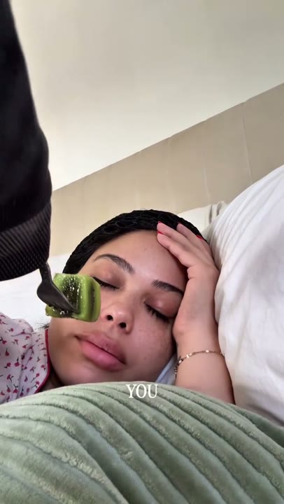 Frame at 3 seconds: An off-camera person offers the kiwi close to the creator's face; the creator declines.