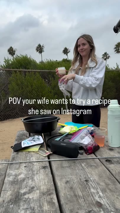 Frame at 1 seconds: The creator smiles and handles ingredients at the picnic table while another person helps.