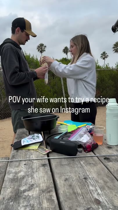 Frame at 2 seconds: The creator smiles and handles ingredients at the picnic table while another person helps.