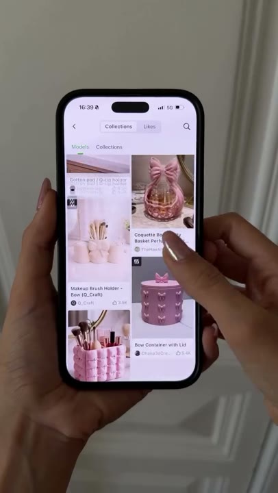 Frame at 3 seconds: Close-up of a phone displaying decorative holders and containers in a model gallery.
